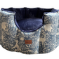 Dog bed with nature-themed fabric and navy interior on a white background